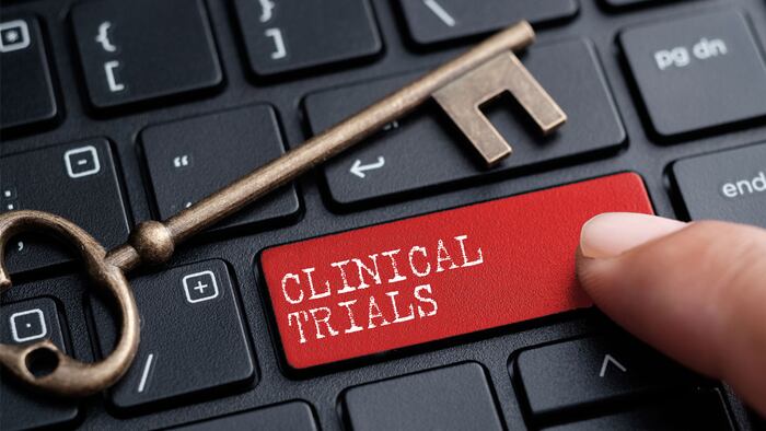 Closed up finger on keyboard with word CLINICAL TRIALS