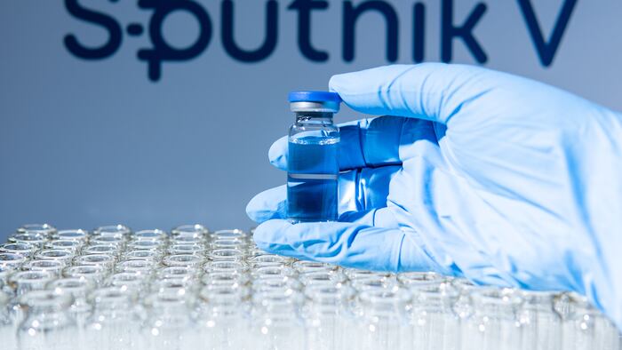 Sputnik V name in blur. Scientist holding the glass vial with Russian vaccine.