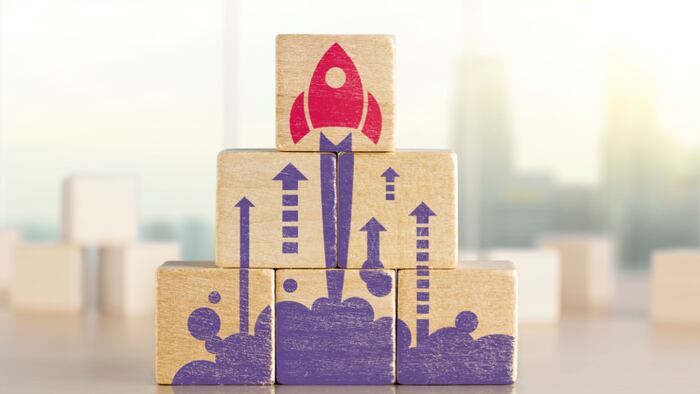 Wooden blocks with launching rocket graphic arranged in pyramid shape
