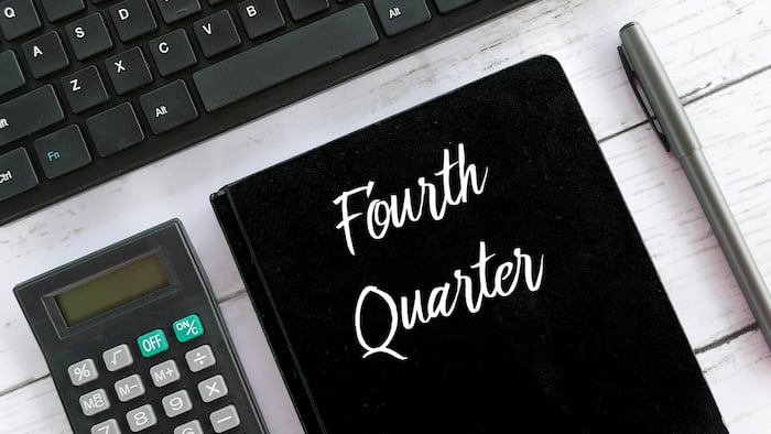 Top view of calculator,keyboard,pen and notebook written with Fourth Quarter.
