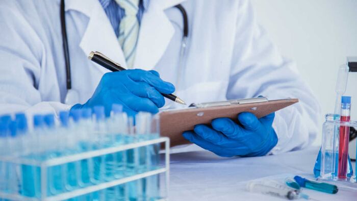 Laboratory worker writes on clipboard, with test-tube rack in the foreground