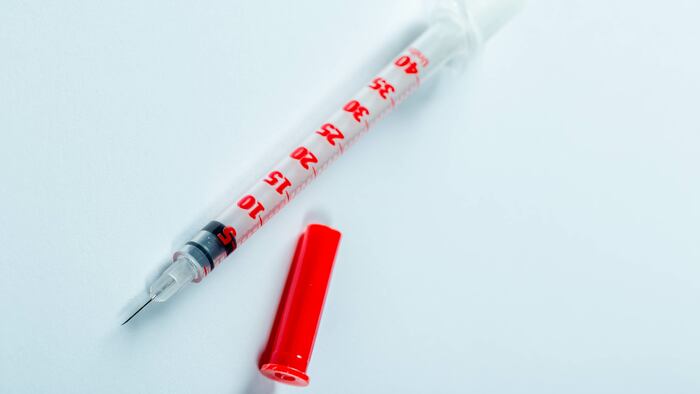 Insulin syringe on light blue background