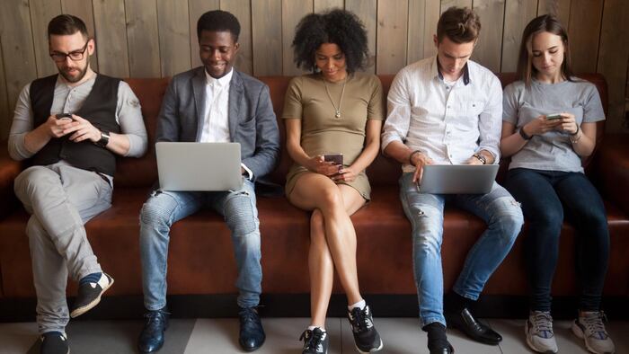Multicultural young people using laptops and smartphones sitting