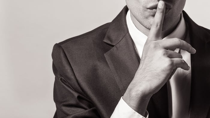 close up of person in business shoot going "shh" with finger