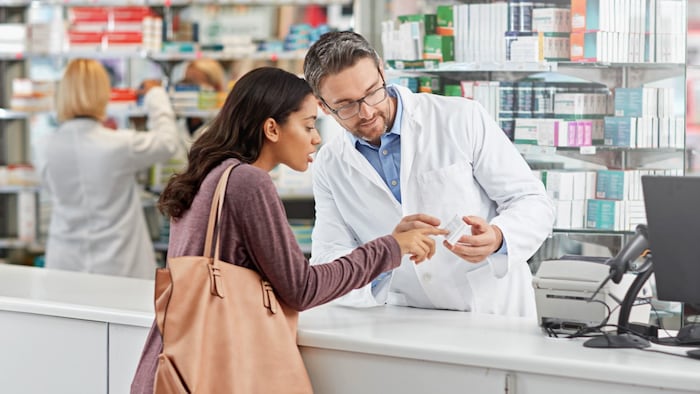 Medicine, help and pharmacist advice with side effects at health store counter for customer service. Pharmaceutical advice and opinion of worker helping girl with medication information at pharmacy.
