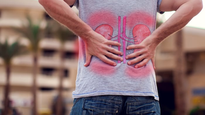 People, health care and medicine concept - unhappy man suffering from pain in back or kidneys sitting on bench on street
