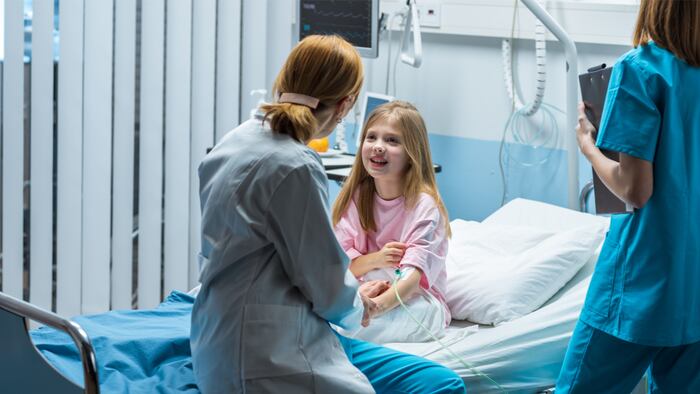 Cute Little Girl Sits on a Hospital Bed and Talks with Friendly Woman Doctor Taking Blood Test. Children's Hospital Pediatric Ward. Top Quality Health Care.
