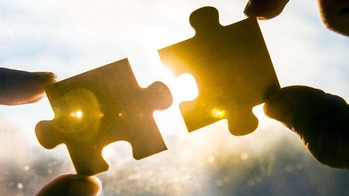 two hands trying to connect couple puzzle piece with sunset background. Jigsaw alone wooden puzzle against sun rays. one part of whole. symbol of association and connection. business strategy.