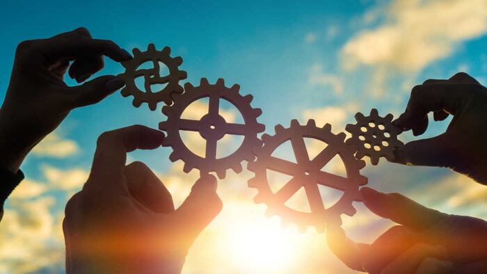 Four hands of businessmen connect gears to a puzzle on a background of sunset. Business concept idea, partnership, cooperation, teamwork, community,