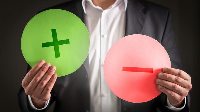 Pros and cons concept. Business man with cardboard plus and minus symbol signs.