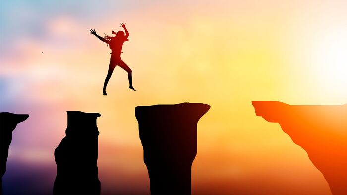 Silhouette woman to jump over obstacles over precipice between rocky mountains A Step to success at background sunset pastel.