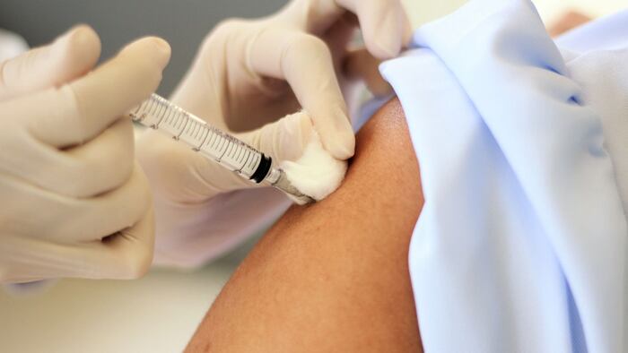 A selective focus at the end of syringe while needle was injected into deltoid muscle and using the cotton to stop bleeding while pulling the needle out