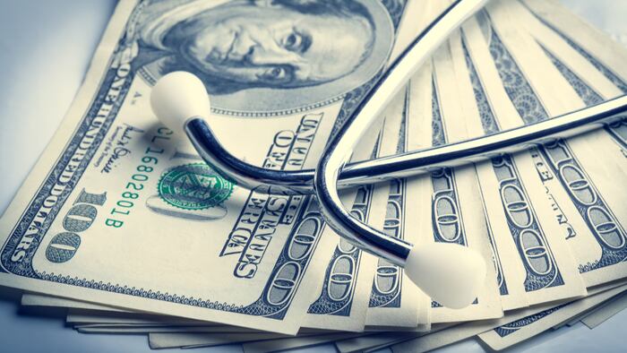 Stethoscope resting on pile of US currency.