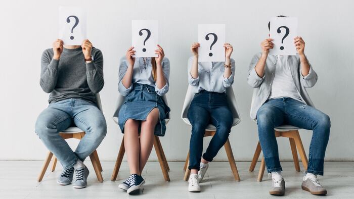 Four people holding up question mark signs