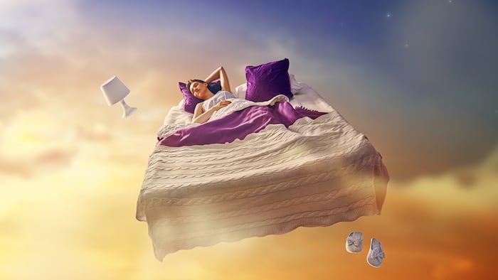 Woman's dreams. Pretty girl is flying in her bed trough star sky.