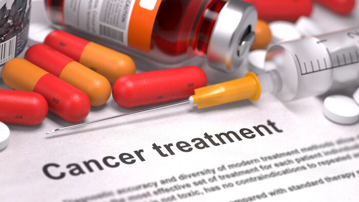 Pills and syringes lying on top of a sheet of paper reading 'Cancer treatment'