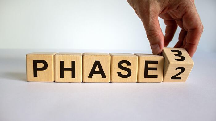 Hand is turning a cube and changes the word 'Phase 2' to 'Phase 3'.
