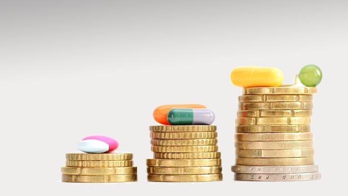 Ladder made of coins with colorful pills on top suggesting the growing prices of medicine or drugs