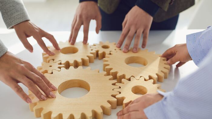 business people stacking cogwheels in team