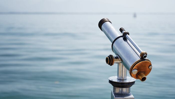 Grey telescope looking out over a body of water
