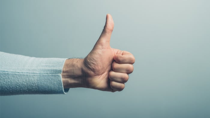 A young man' hand is displaying a thumbs up, indicating that he likes or approves of something - Image