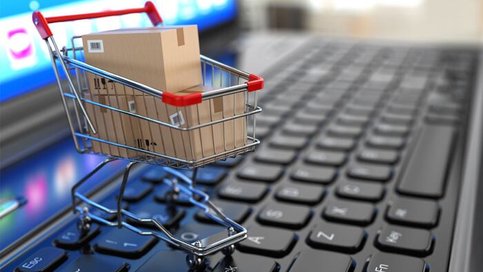 E-commerce. Shopping cart with cardboard boxes on laptop. 3d