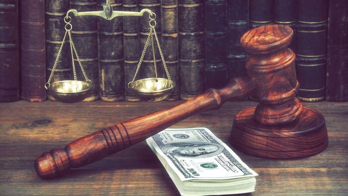 Cavel next to wad of dollar notes and gold scales of justice