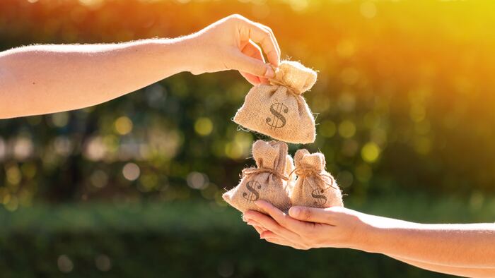 A man and a women hands hold a money bags in the public park for loans to planned investment in the future concept.