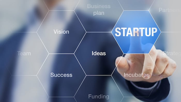Startup button on a virtual screen touched by a businessman, concept about small fast growing businesses