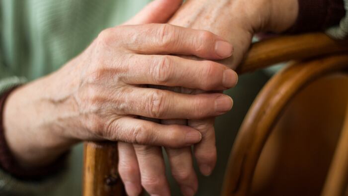 two hands of an elderly woman sitting on a chair - Image