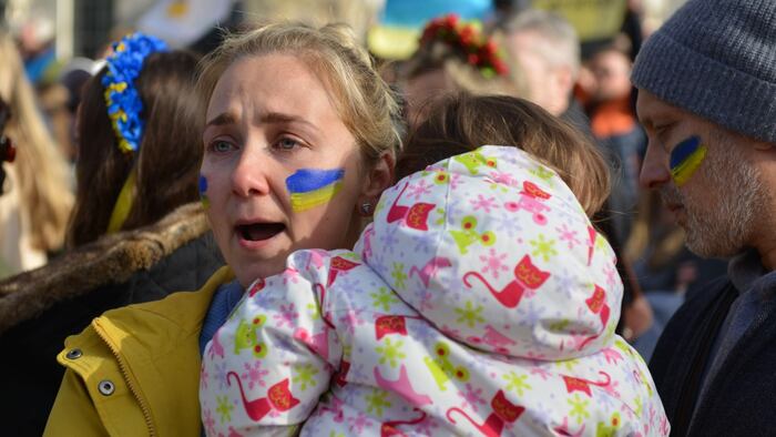 Woman with Ukraine flag painted on cheek protesting Russian invasion