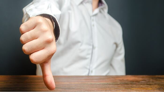 A man shows a thumb down. Gesture of disapproval and rejection. Bad assessment, harsh criticism, failure and defeat. Refusal to pass and cooperation. Bureaucratic obstacles. Contempt and condemnation