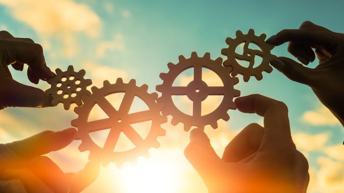 four hands of businessmen connect gears