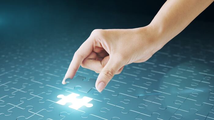Hand placing jigsaw puzzle piece into gap