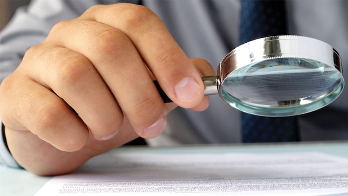 Businessman looking through a magnifying glass to documents