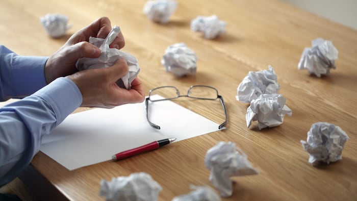 hand throwing ball of paper into wastebasket